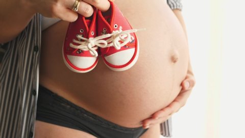 Female hands showing baby little shoes Close up newborn Pregnancy concept