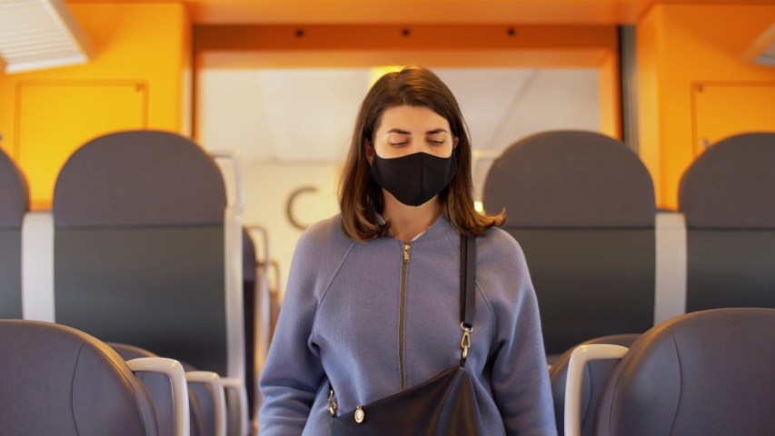 health, safety and pandemic concept - young woman in protective black face mask in electric train