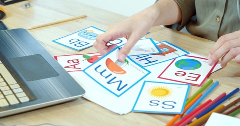Close-up of multi-colored cards with letters and drawings on the table. Learning the alphabet or English. Online education