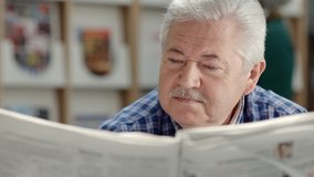 Retired senior man with mustache reading newspaper in public library. Active old people and education, elderly guy reading news in paper during free time - Powered by Shutterstock - Get 15% off with code: PIKWIZARD15