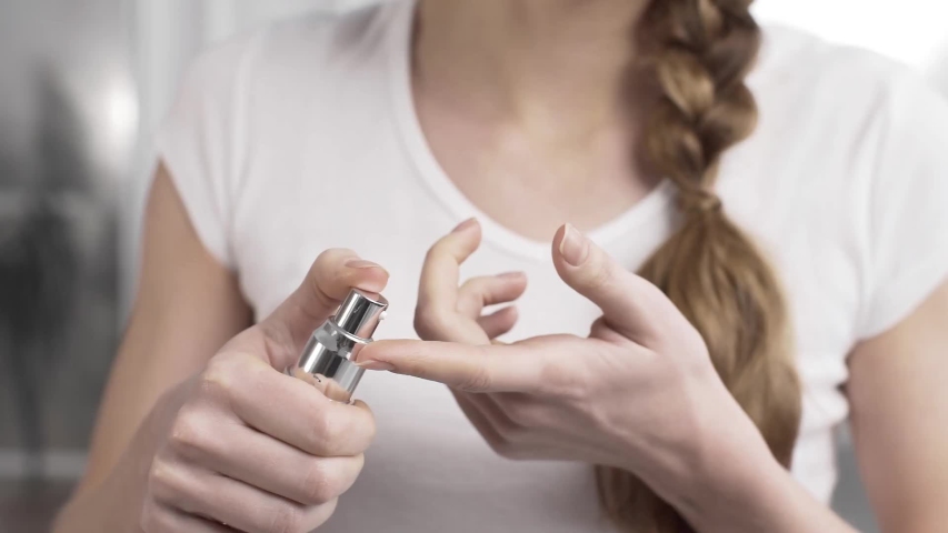 woman squeezes a drop of cream from the bottle dispenser 