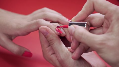 manicurist paints clients nails with beige tint nail polish 