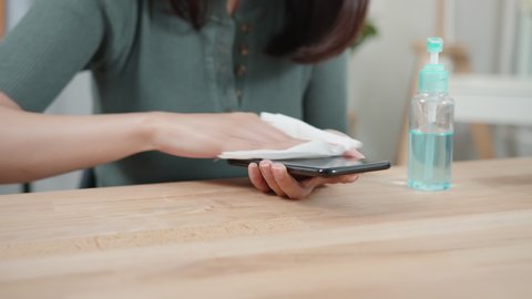 Asian Woman cleaning smartphone screen with alcohol. Disinfecting mobile phone for disease prevention from virus and bacteria. woman hand wipe and sanitizer to clean phone. Virus pandemic protection