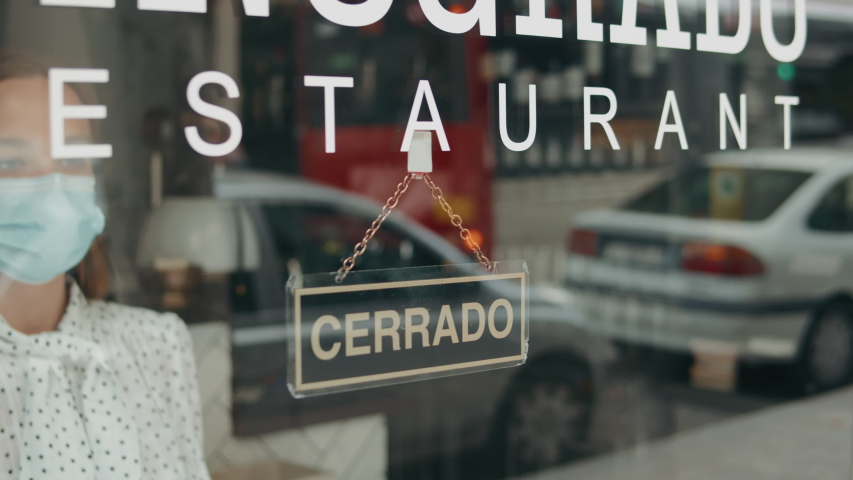 Cafe or restaurants and business reopen after coronavirus quarantine is over. woman with face mask turning a sign from closed to open on a door shop. small business after post covid lockdown. Spain | Shutterstock HD Video #1053618533