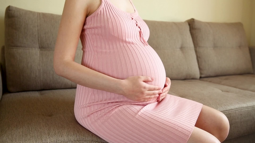A pregnant woman scratching her belly with her hand. The girl