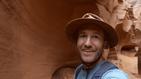 Cheerful young man taking a selfie portrait with the beautiful landscape of Antelope Canyon in Arizona, USA People travel nature communication concept