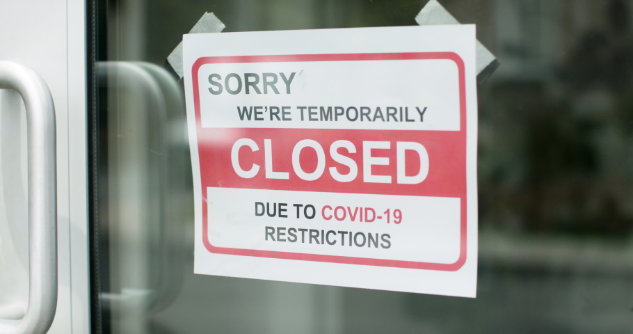 Closed for business due to covid. Small shop puts closed sign up on storefront. Shot in 4k.  Royalty-Free Stock Footage #1053621872