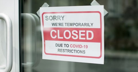 Closed for business due to covid. Small shop puts closed sign up on storefront. Shot in 4k. 