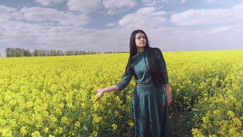 Shooting a clip in nature. The girl is dancing smoothly in a flowering field. In the frame, the camera is also visible to the steadicam.