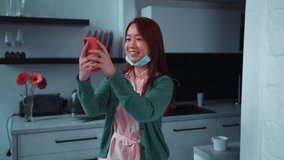 Asian cute girl using smartphone for video chat call with friend, showing her kitchen around, blogging for social media at home. Online communication. Social distance. Quarantine.