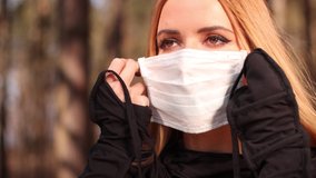 Video 4K, a young blonde woman with long hair removes a protective white mask from her face on a sunny day in spring