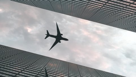 Airplane flies over office skyscrapers against a beautiful sky