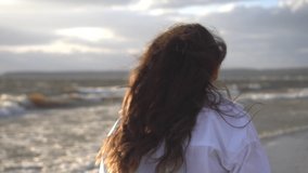 Playful young woman enjoying summer vacation at summer beach. Sensuous female with windswept hair is walking on beach at island wearing in a white shirt by sea. - Powered by Shutterstock - Get 15% off with code: PIKWIZARD15