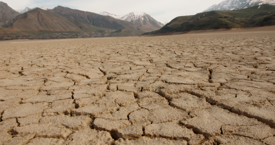 Dynamic shot of cracked soil ground of dried lake or river in mountains. Land destroyed by erosion and global warming - ecological issues concept 4k footage | Shutterstock HD Video #1053645419