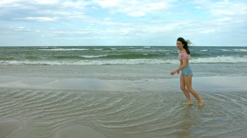 Brunette dancer jumping and dancing in slow motion on the sea shore.