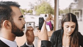 Wide 4k video of middle eastern using app, with hand gestures on smartphone in coffee cafe wile in meeting with business woman. 