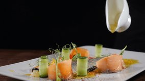 Slow motion food video in restaurant. Close-up shot of chef pouring extra virgin olive oil on fish snack served with vegetables. Sliced herring put on white plate. Full hd