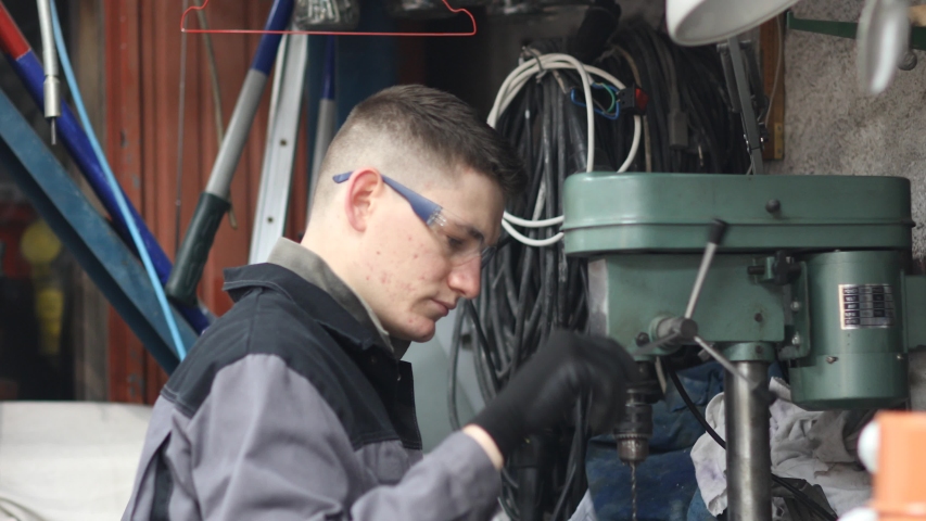Mechanic wearing glasses working at drilling machine