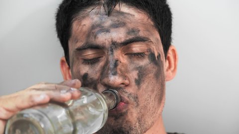Drunkard Homeless Dirty young Man Drinks an Alcoholic Drink. The Problem of Alcohol Addiction. Withdrawal Pains. Close up. portrait. On white background.