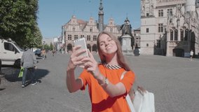 beautiful smiling young woman using mobile phone - female tourist taking selfie and recording video in city center