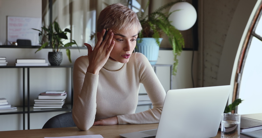 Concerned stressed young business woman feeling tired thinking of difficult online problem solution looking at laptop at workplace. Serious female employee frustrated about overwork in office concept. | Shutterstock HD Video #1053655295