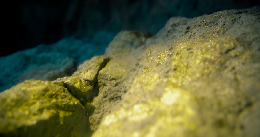 Camera slide on a mine wall with gold nuggets 