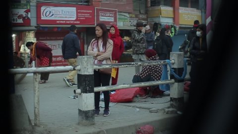 Kathmandu, Nepal - 22 November 2019: A view from a moving car on nepali sidewalk. Beggar, sad, unhappy pedestrians. Dirty pavement.