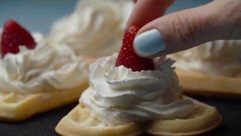 Homemade waffles with whipped cream topping rotating. Fresh strawberries putting on white cream waffles top in slow motion.