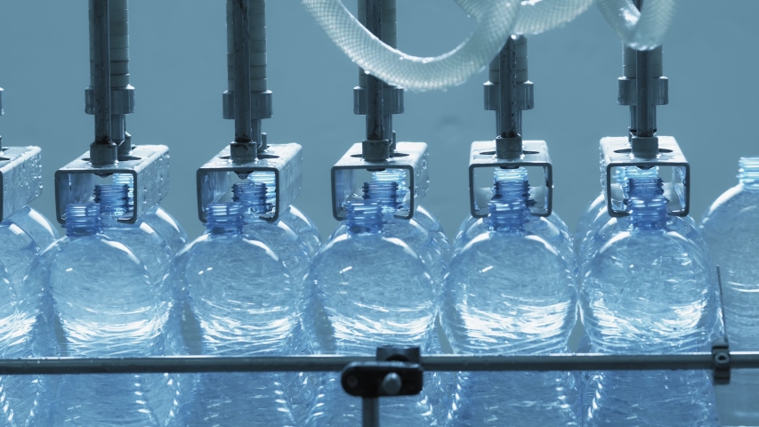 Automatic conveyor line for bottling mineral water in the plastic bottle. Line for PET bottle water. Water factory-bottling pure spring water into bottles. Selective focus. | Shutterstock HD Video #1053665651