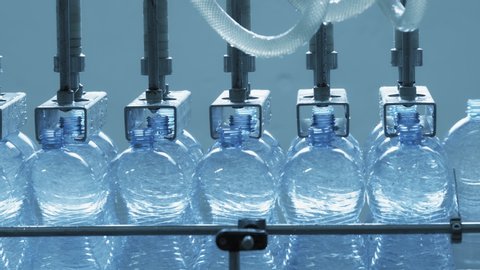 Automatic conveyor line for bottling mineral water in the plastic bottle. Line for PET bottle water. Water factory-bottling pure spring water into bottles. Selective focus.
