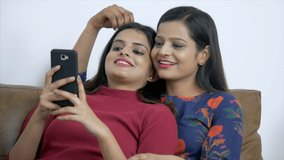 Indian LGBTQ couple watching videos on the phone while caressing each other. HD Stock Video of an Indian girl couple lying together on the couch and having a good time - LGBTQ couple's lifestyle in...