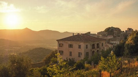 Time lapse of sun setting over the mountain village of Belgodere in the Balagne region of Corsica with the Mediterranean coast in the distance