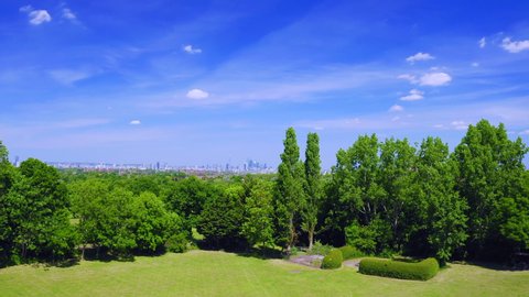 Aerial shots of a park in London during a sunny day. Showing the parks and heading high showing London in the distance. The characteristic antenna of Crystal Palace in view and Dulwich area