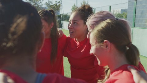 Manager joining hands with womens soccer team during motivational pep talk before match - shot in slow motion