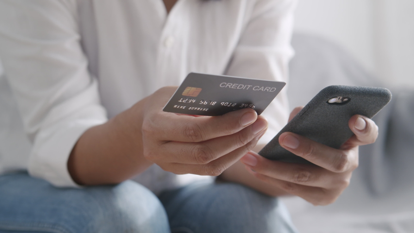 Side view. Hand of young women are buying online with a credit card. woman are using smartphone and doing online transactions at home. Concept of shopping online by technology and lifestyle new normal | Shutterstock HD Video #1053684614