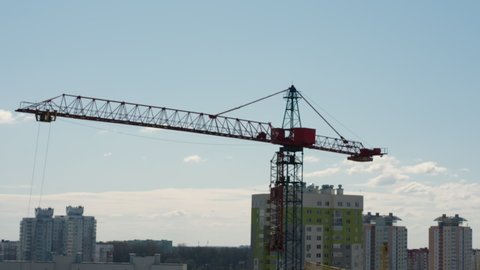 modern high building crane operates transporting special concrete details on construction site against floating clouds timelapse