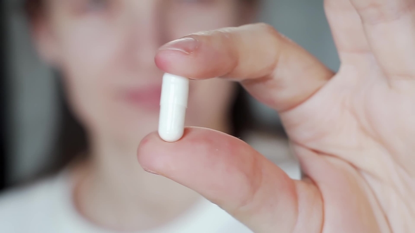 young woman taking medicine painkiller pills with water. stressed person showing close a capsule and taking antidepressant or supplement. addiction, health care, medicare, pharmacy and treatment
