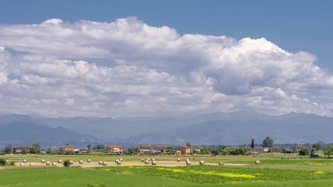 Beautiful landscape in the Tuscan countryside between the provinces of Pisa, and Lucca with hay bales in the foreground and Mount Abetone in the background, Italy, time lapse motion