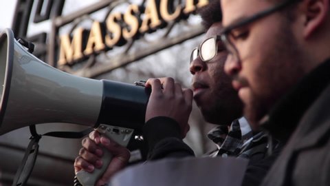 Boston, MA / USA - March 12, 2015: A protestor uses a megaphone to make a speech in front of a crowd at a Black Lives Matter protest on the steps of the Massachusetts State House.