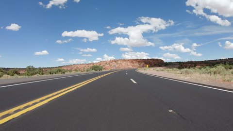 POV Driving a car on curvy asphalt Arizona road with rocky mountains near Grand Canyon. Blue sky with white clouds