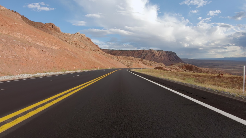POV Driving a car going down on asphalt Arizona road with rocky mountains. Sunny sky with white clouds | Shutterstock HD Video #1053702260