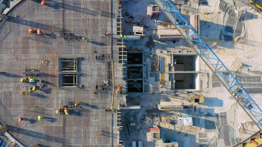 Aerial top down view on the rooftop of an office skyscraper in a course of building (under construction) with a lot of workers Royalty-Free Stock Footage #1053702326