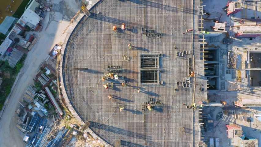 Aerial top down view on the rooftop of an office skyscraper in a course of building (under construction) with a lot of workers | Shutterstock HD Video #1053702326