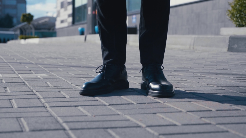 Front view feet of businessman commuting to work. Confident guy in leather shoes and a suit walks along the street of the business district | Shutterstock HD Video #1053706526