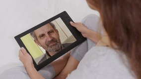 Young adult woman daughter calling older father on laptop computer screen. woman talking by webcam. Videocall, family chat concept. Over shoulder close up view.