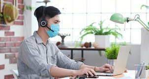 asian business man is self quarantine - he work from home and wear facial mask with laptop