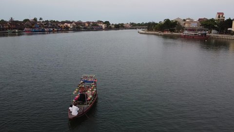 Aerial: Folllowing a tourist wooden boat in the Thu Bon river in Hoi An, Vietnam