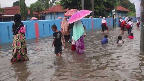 Residents and school children when passing through flooded roads with still rainy conditions, Pekalongan, February 24, 2020