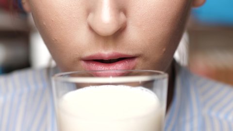 Woman is drinking milk. Female hand holds glass to his mouth and drinks milk