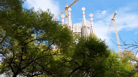 Barcelona, Catalunya / Spain - 24.01.2020: Gimbal reveal shot of Sagrada Familia with tree canopy in foreground